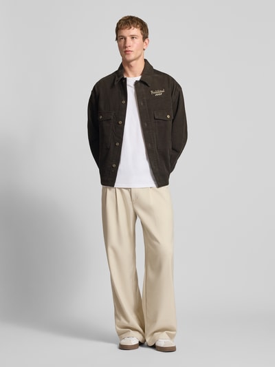 Männermodel trägt Wide Leg Hose mit Eingrifftaschen von PROHIBITED, beige, aus Material-Mix mit Viskose-Anteil, Ganzkörperansicht von vorne.