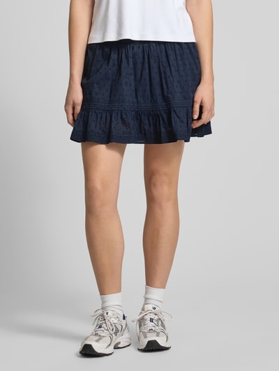 Frauenmodel trägt Regular Fit Mini-Skort aus reiner Baumwolle Modell 'KATTI' von Only, Optik: Unifarben, Strukturmuster gestickt, Bundabschluss gesmokt, feine Webstruktur, Mini-Länge, ausgestellt, Ganzkörperansicht von vorne.
