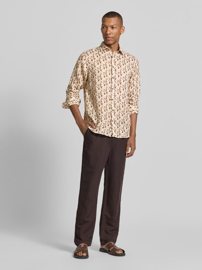 Männermodel trägt Slim Fit Freizeithemd aus reinen Leinen Modell 'Gold' von bugatti mit floraler Allover-Print, Kentkragen, Langärmelig, durchgängige Knopfleiste, Rückenlänge bei Größe M: 78 cm, Schulterbreite: 45 cm, Ärmellänge: 68 cm, Beige- und Brauntöne, leichte Textur; Ganzkörperansicht von vorne.