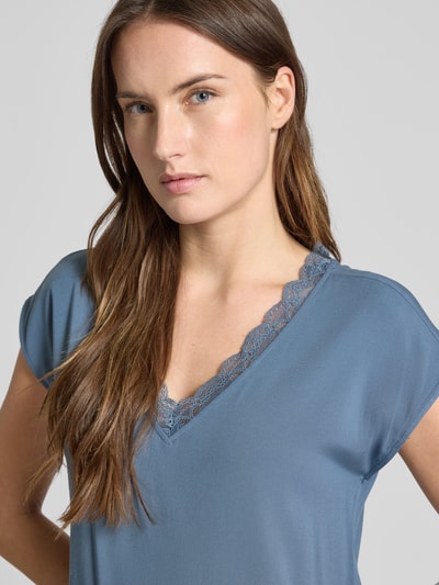Kobiece modelka nosi Regular Fit T-Shirt mit Spitzenkragen Modell 'BELLA' von Vero Moda, jednolity, jersey stretch, krótki rękaw, niebieski, dekolt V z koronką, wiskozowy miks, zbliżenie na górną część ciała
