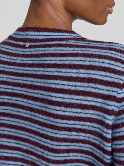 Frauenmodel trägt Strickjacke mit Woll-Anteil Modell 'Milvi' von MOS MOSH, gestreift in Blau und Bordeaux, Detailaufnahme Rücken, Material-Mix, gerippter Rundhalsausschnitt, taillierte Passform, KI-modifiziertes Bild.