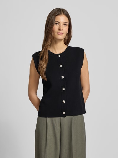 Frauenmodel trägt Regular Fit Strickjacke aus Viskose-Mix Modell 'GOLD' von Vero Moda in Schwarz, Strickoptik, Nahaufnahme Oberkörper.