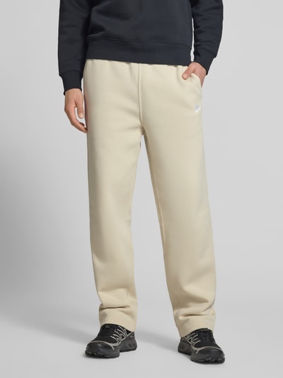 Männermodel trägt Sweatpants mit Logo-Stitching und Eingrifftaschen von Nike aus Baumwoll-Mix in Loose-Fit, Nahaufnahme Unterkörper.