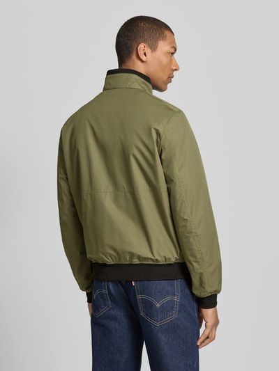 Männermodel trägt Regular Fit Jacke mit Stehkragen von MCNEAL in Oliv mit Reißverschluss, elastische Abschlüsse, Rückenansicht. Rückenlänge 64 cm, Schulterbreite 43 cm, Brustweite 55 cm, Ärmellänge 67 cm.