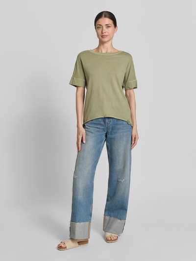Modelka nosi Relaxed Fit T-Shirt aus reiner Baumwolle od s.Oliver RED LABEL, kolor jednolity, krój relaxed fit, okrągły dekolt, krótki rękaw, bawełna, detal z logo, widok całej sylwetki z przodu.