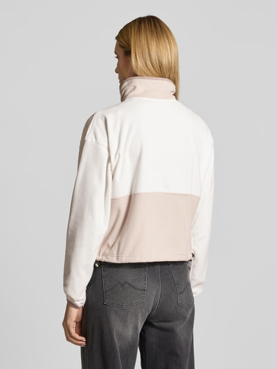 Frauenmodel trägt Cropped Fleecejacke mit Label-Patch Modell 'Backbowl™' von COLUMBIA, beżowe i kremowe kolory, krój regular fit, stójka, zamek, elastyczne mankiety, kieszenie, długość tyłu w rozmiarze S: 52 cm, szerokość ramion w rozmiarze S: 55 cm, szerokość klatki piersiowej w rozmiarze S: 57 cm, długość rękawa w rozmiarze S: 56 cm, całkowity widok z tyłu.