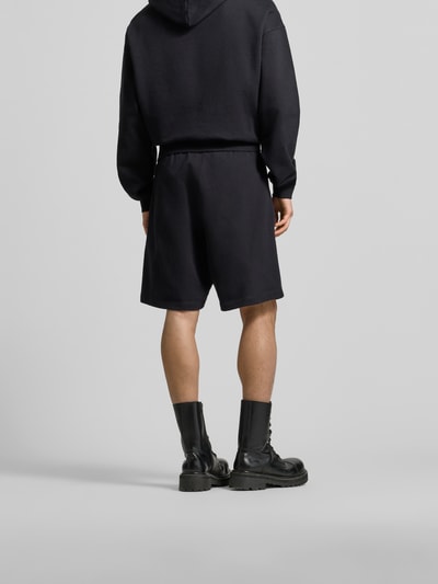 Männermodel trägt Sweatshorts aus reiner Baumwolle von Dsquared2 in Schwarz, elastischer Bund, gerade Passform, Ganzkörperansicht Rückansicht.
