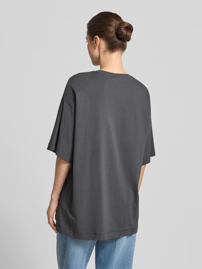 Frauenmodel trägt Oversized T-Shirt aus reiner Baumwolle Modell 'LILIE' von Vero Moda, Optik: Unifarben, Passform: Oversized, Motiv-Print, Ärmel Kurzarm, Material: Reine Baumwolle, Ganzkörperansicht Rückansicht.