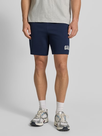 Männermodel trägt navyblaue Straight Fit Shorts mit Logo-Stitching Modell 'Heritage' von GAP in Baumwoll-Mix, Ganzkörperansicht von vorne.