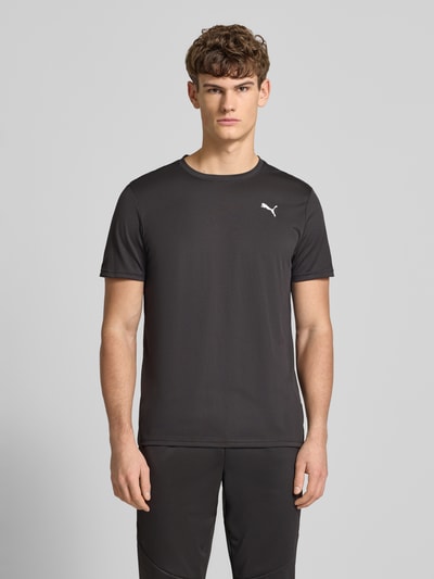 Męski model nosi T-Shirt z logo i okrągłym dekoltem od PUMA PERFORMANCE, czarne, regular fit, widok całej sylwetki z przodu.