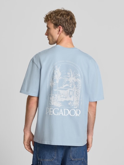 Männermodel trägt Oversized T-Shirt mit Backprint und Rundhalsausschnitt von PEGADOR, hellblau, reine Baumwolle, Rückansicht, Ganzkörperansicht.
