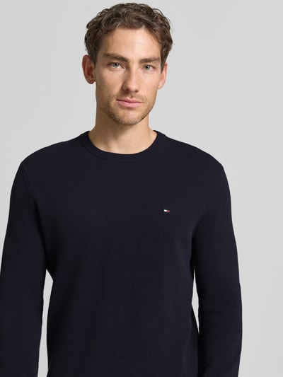 Männermodel trägt Regular Fit Pullover aus reiner Baumwolle von Tommy Hilfiger in Dunkelblau, strukturierte Oberfläche, Nahaufnahme Oberkörper.