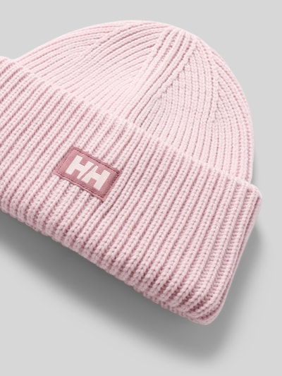 Produktfoto, Beanie in Strick-Optik mit Logo-Patch von Helly Hansen in zartem Rosa, Strukturmuster, Fixierter Bund, grauer Hintergrund