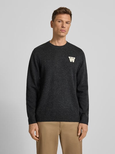 Männermodel trägt Strickpullover aus Lammwolle Modell 'Tay' von Wood Wood, Regular-Fit, Rundhalsausschnitt, Label-Stitching, Ganzkörperansicht von vorne.