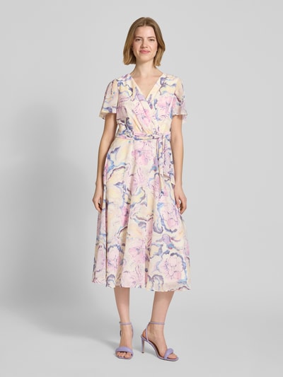 Frauenmodel trägt Midikleid mit floralem Allover-Print von Christian Berg Cocktail in Pastellfarben, Tailliert, V-Ausschnitt, Falten-Optik, Kurzärmelig, Stoffband, Ganzkörperansicht von vorne.