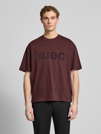 Männermodel trägt Oversized T-Shirt aus reiner Baumwolle Modell 'DINKEE' von HUGO, unifarben, Label Print, Rundhals, Kurzarm, Ganzkörperansicht von vorne.