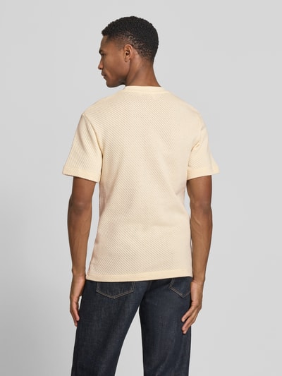 Męski model nosi Regular Fit T-Shirt aus reiner Baumwolle od Lacoste, jasny beż, krój regular fit, struktura dzianiny, widok całej sylwetki z tyłu.