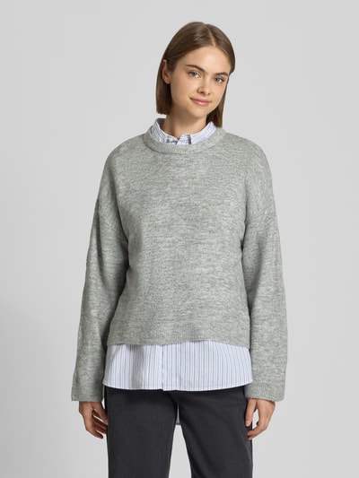 Modelka nosi szary sweter z okrągłym dekoltem, model 'SIMONI' od ONLY, sweter damski, widok całej sylwetki z przodu.