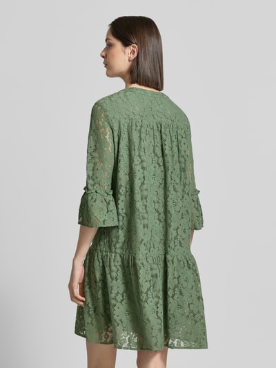 Frauenmodel trägt Loose Fit Spitzenkleid aus Baumwoll-Mix Modell 'HONEY' von Vero Moda in Unifarben mit Spitzen-Muster, knielang, 3/4-Arm, Glockenärmel, Materialverarbeitung Spitze, Rückansicht.