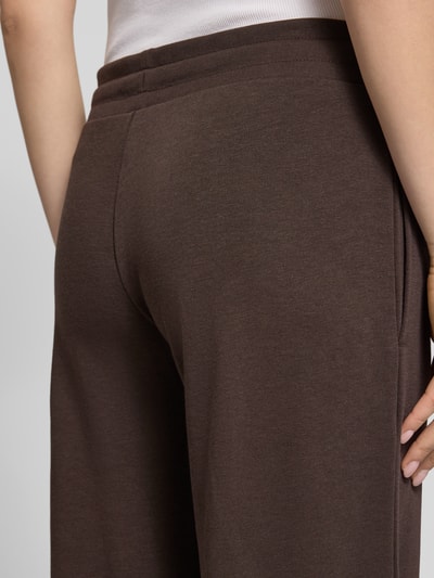 Frauenmodel trägt Straight Fit Sweatpants mit Tunnelzug von REVIEW aus mieszanka bawełny, kolor brązowy, z prostymi nogawkami, pas z tunelem, długość wewnętrzna nogawki w rozmiarze S: 85 cm, detailaufnahme tyłu bioder.