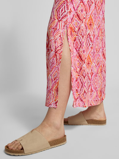 Vrouwenmodel draagt Ausgestellter Maxi-Rock aus reiner Viskose Modell 'EASY JOY' van Vero Moda met grafisch all-over patroon in roze, elastische tailleband, popeline structuur, maxi lengte, detailopname benen.