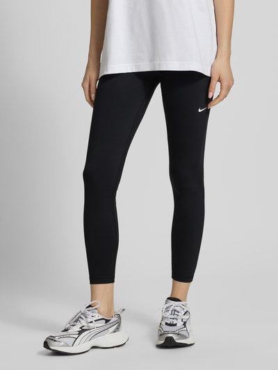 Frauenmodel trägt Leggings mit elastischem Bund und Logo von NIKE TRAINING, Material-Mix mit Stretch-Anteil, Körpernahe Passform, Nahaufnahme Unterkörper.