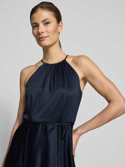 Frauenmodel trägt Cocktailkleid aus Satin mit Bindegürtel von Jake*s Cocktail, dunkelblau, Neckholder, A-Linie, Nahaufnahme Oberkörper.