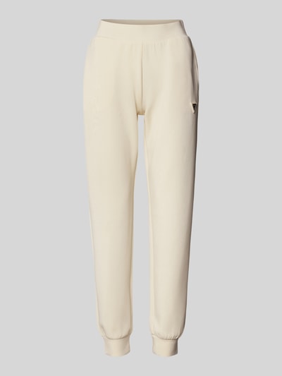 Produktfoto, cremefarbene Sweatpants mit Label-Detail Modell 'OLYMPE' von Guess Activewear, elastischer Bund, körpernaher Schnitt, Material-Mix.