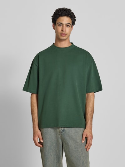Männermodel trägt Oversized T-Shirt mit Rundhalsausschnitt von PROHIBITED aus Reine Baumwolle in Dunkelgrün, Ganzkörperansicht von vorne.