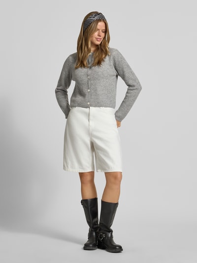Frauenmodel trägt graue Strickjacke mit Woll-Anteil Modell 'SILLY' von PIECES, kombiniert mit weißen Shorts, Ganzkörperansicht von vorne. Damen Strickjacke.