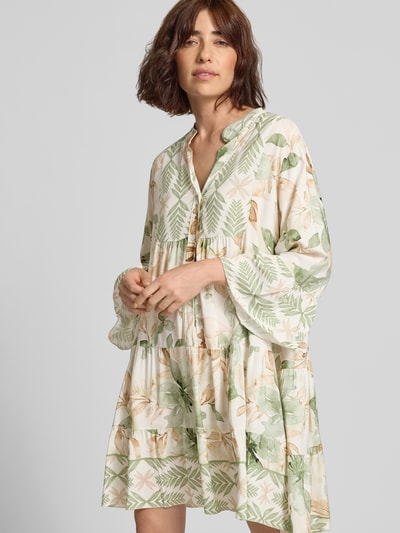 Frauenmodel trägt Minikleid aus Viskose mit Serafino-Kragen Modell 'Ge44rdaa' von ZABAIONE in Grün und Beige, florales Muster, Loose Fit, Ganzkörperansicht von vorne.