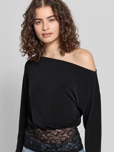 Vrouwenmodel draagt Longsleeve met asymmetrische hals model 'Mirelin' van Gina Tricot, materiaalmix met stretch, nauwsluitend model, kant, ruglengte maat S 52 cm, zwart, zachte textuur, kleurcontrast door kanten detail. Nahaufnahme Oberkörper.