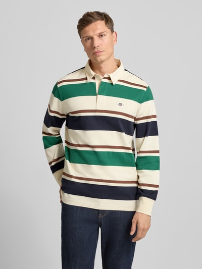Męskimodel nosi Bluza z kołnierzykiem polo i wyhaftowanym logo od Gant, bawełna, krój regular fit, długość tyłu 76 cm, długość rękawów 65 cm, zdjęcie przód, ujęcie całej sylwetki.