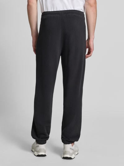 Männermodel trägt Sweatpants mit Eingrifftaschen Modell 'ATUBAY' von American Vintage, Schwarz, Baumwoll-Elasthan-Mix, Relaxed-Fit, elastischer Bund, Tunnelzug, Innenbeinlänge 77 cm, Ganzkörperansicht Rückansicht.