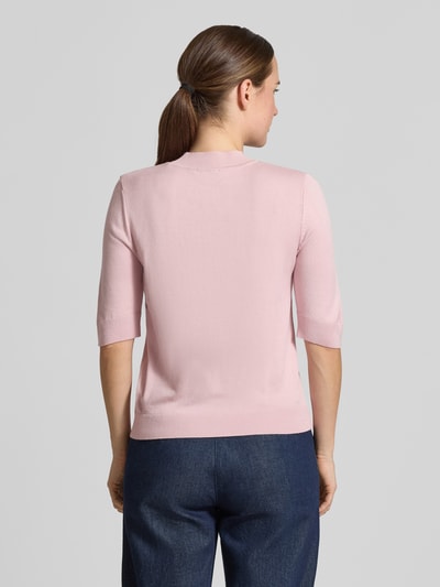 Frauenmodel trägt Strickpullover aus Viskose-Mix von MORE & MORE in zartem Rosa, taillierte Passform, Rückenansicht, Kontext: Damen Strickpullover, Viskose-Elasthan-Mix, Stehkragen, gerippte Abschlüsse, Halbarm, Rückenlänge 50 cm, Ärmellänge 30 cm. Ganzkörperansicht Rückansicht.