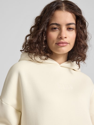 Frauenmodel trägt Relaxed Fit Sweatshirt mit Logo-Print von Review, Baumwoll-Mix, Logo-Stitching, elastische Abschlüsse, Nahaufnahme Oberkörper.