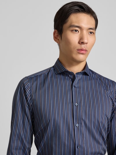Männermodel trägt Slim Fit Business Hemd mit Haifischkragen von OLYMP Level Five, Reine Baumwolle, durchgängige Knopfleiste, langärmelig, Sportmanschetten, vertikale Streifen in Blau und Weiß, Nahaufnahme Oberkörper.