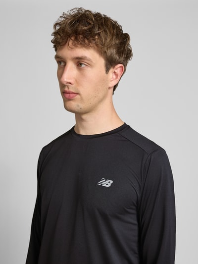 Männermodel trägt Funktionsshirt mit Rundhalsausschnitt und Logo von New Balance in Schwarz, Herren, Regular-Fit, Longsleeve, Nahaufnahme Oberkörper. Rückenlänge bei Größe M: 72 cm.