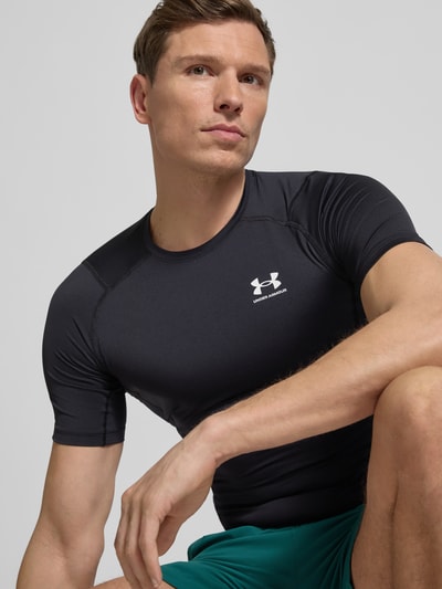 Männermodel trägt Slim Fit T-Shirt mit Logo-Print von Under Armour, elastischer Material-Mix, Rundhalsausschnitt, Nahaufnahme Oberkörper.