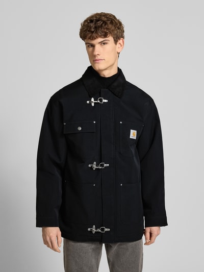 Männermodel trägt Oversized Jacke mit Logo-Patch Modell 'Adair' von Carhartt Work In Progress, Schwarz, Umlegekragen, Ganzkörperansicht von vorne.