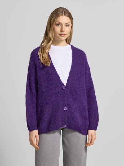 Frauenmodel trägt Cardigan mit V-Ausschnitt Modell 'EAST' von American Vintage in Lila, Relaxed Fit, weiche Textur, Ganzkörperansicht von vorne.