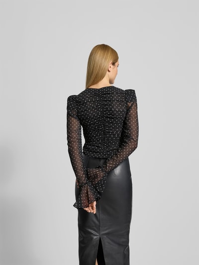 Frauenmodel trägt Slim Fit Bluse mit Raffungen von ROTATE aus schwarzem Chiffon mit weißen Punkten, langärmelig, Rückenlänge 47 cm, Reißverschluss, Ganzkörperansicht Rückansicht.