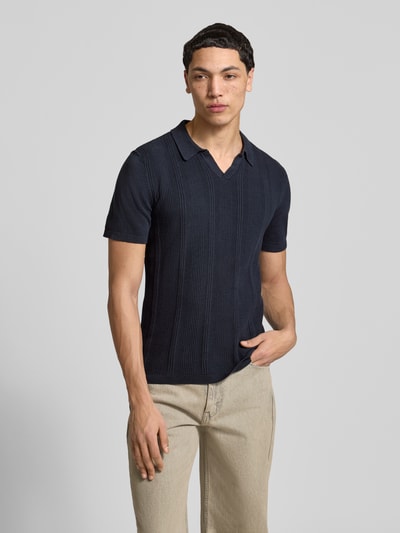 Męski model nosi Slim Fit Poloshirt in Strick-Optik Modell 'Baron' von Blend, granatowa bawełna, kołnierzyk polo, krój slim fit, długość tyłu w rozmiarze M: 65 cm, imitacja dzianiny, całkowity widok z przodu.