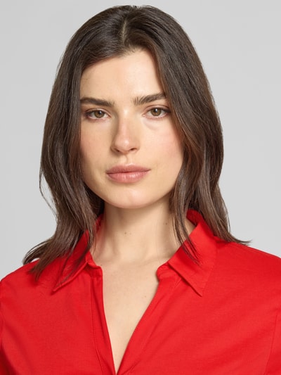 Frauenmodel trägt Regular Fit Hemdbluse in langärmeligen Design Modell 'Februar' von More & More im Baumwoll-Mix, Nahaufnahme Oberkörper. Damen Hemdbluse, Hemdblusenkragen, durchgängige Knopfleiste, taillierte Passform, Rückenlänge 65 cm, Ärmellänge 60 cm, intensive rote Farbe, glatte Textur.