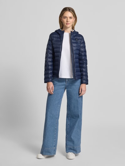Frauenmodel trägt Steppjacke mit Zweiwege-Reißverschluss Modell 'ELLIS' von Blauer Usa, dunkelblau, glänzende Textur, Ganzkörperansicht von vorne, Slim Fit, Kapuze, für Damen.