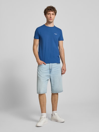Männermodel trägt Slim Fit T-Shirt aus Baumwoll-Mix Modell 'ORIGINAL BASIC 3N' von Pepe Jeans, unifarben blau, Ganzkörperansicht von vorne.