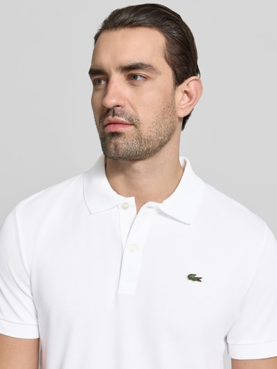 Männermodel trägt Regular Fit Poloshirt aus reiner Baumwolle von Lacoste, Optik: Unifarben, Logo-Detail, Nahaufnahme Oberkörper.