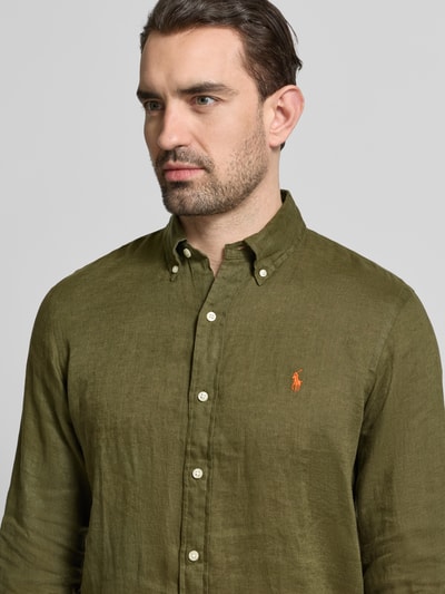Männermodel trägt Regular Fit Freizeithemd aus reinem Leinen von Polo Ralph Lauren in Olivgrün mit Logo-Detail, Nahaufnahme Oberkörper.