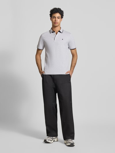 Männermodel trägt Slim Fit Poloshirt mit Viskose-Anteil Modell 'Paulos' von JACK & JONES, hellgrau, Logo-Stitching, Baumwoll-Mix, Ganzkörperansicht von vorne.