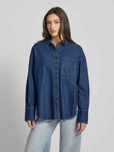 Frauenmodel trägt Oversized Jeansbluse mit Brusttasche von REVIEW in Dunkelblau, reine Baumwolle, Hemdblusenkragen, Ganzkörperansicht von vorne.